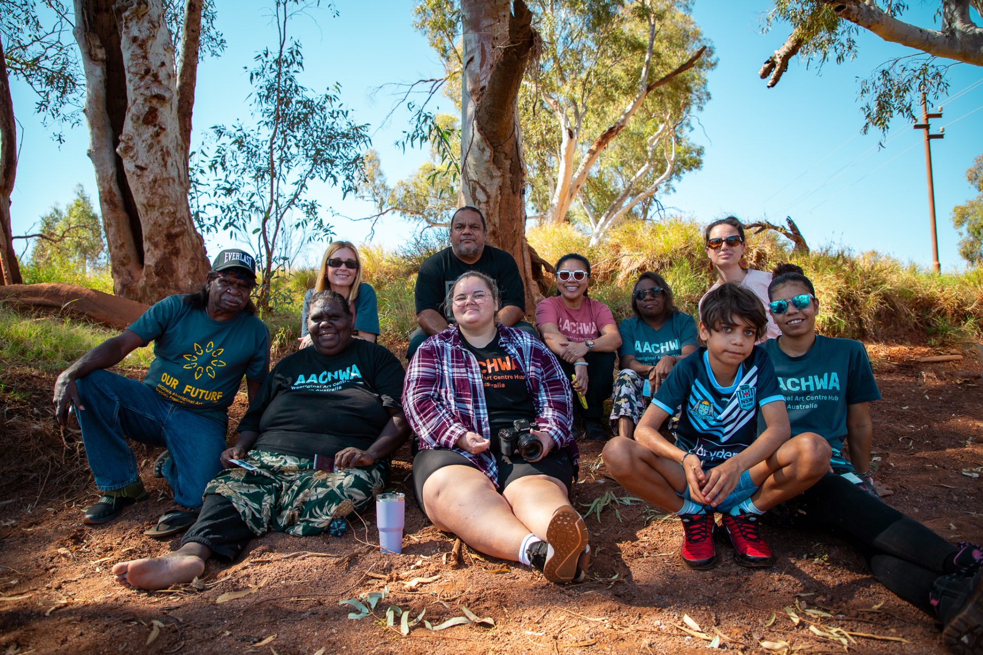 Back: Emily Coy (AACHWA Program Coordinator), Michael Torres (Photographer/Facilitator), Jacky Cheng (Facilitator), Sylvia Wilson, Glenda Dixon (AACHWA Program Manager); Front: Henry Farmer, Julieanne Farmer, Rekeshia Goodwin, Ruby Djikarra Alderton, Our Future: Aboriginal Arts Worker Training Program at Sandy Creek, Nyiyaparli Country (Newman). Photograph by Jessica Russell.