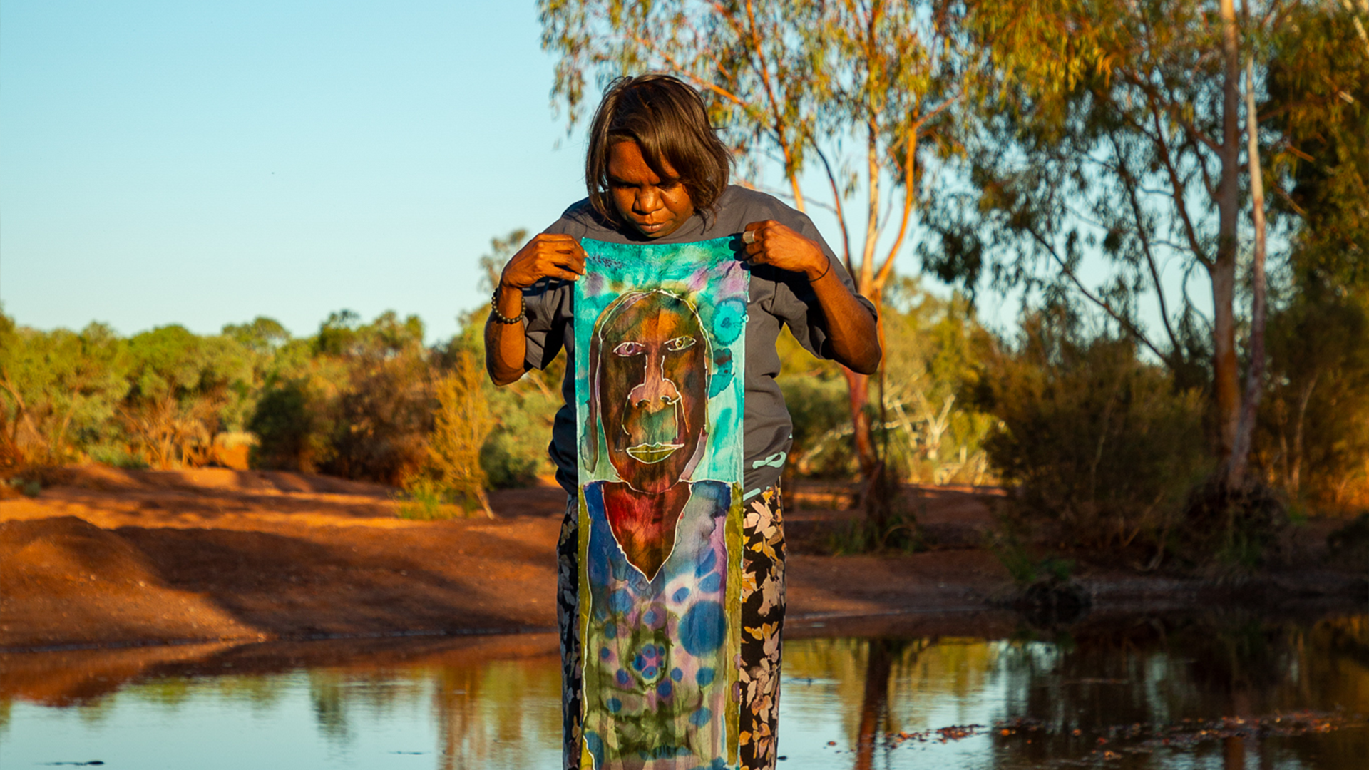 Sylvia Wilson with her silk painting, Our Future: Aboriginal Arts Worker Training Program at Sandy Creek, Nyiyaparli Country (Newman). Photograph by Jessica Russell.