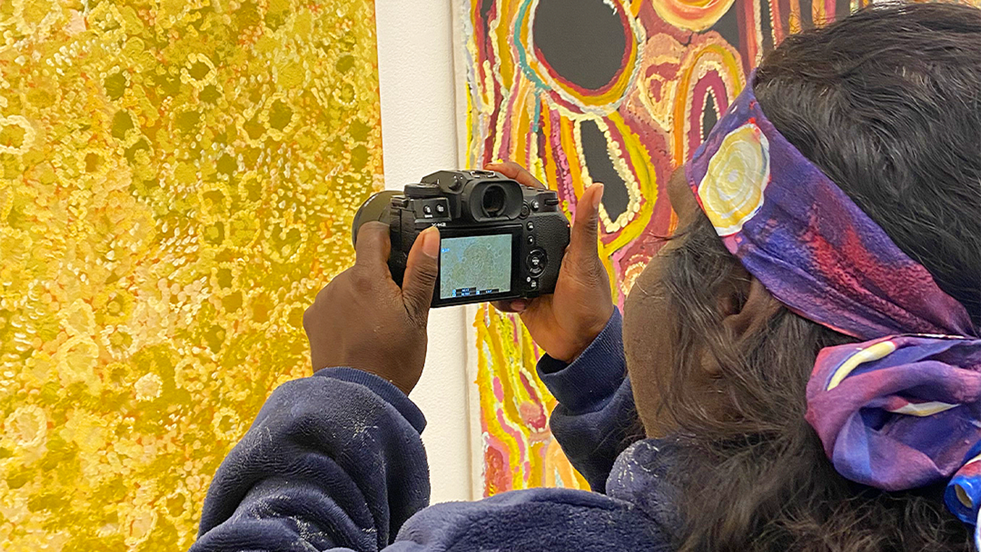 Julieanne Farmer photographing artwork detail, Our Future: Aboriginal Arts Worker Training Program at Martumili Artists, Nyiyaparli Country (Newman). Photograph by Jessica Russell. 