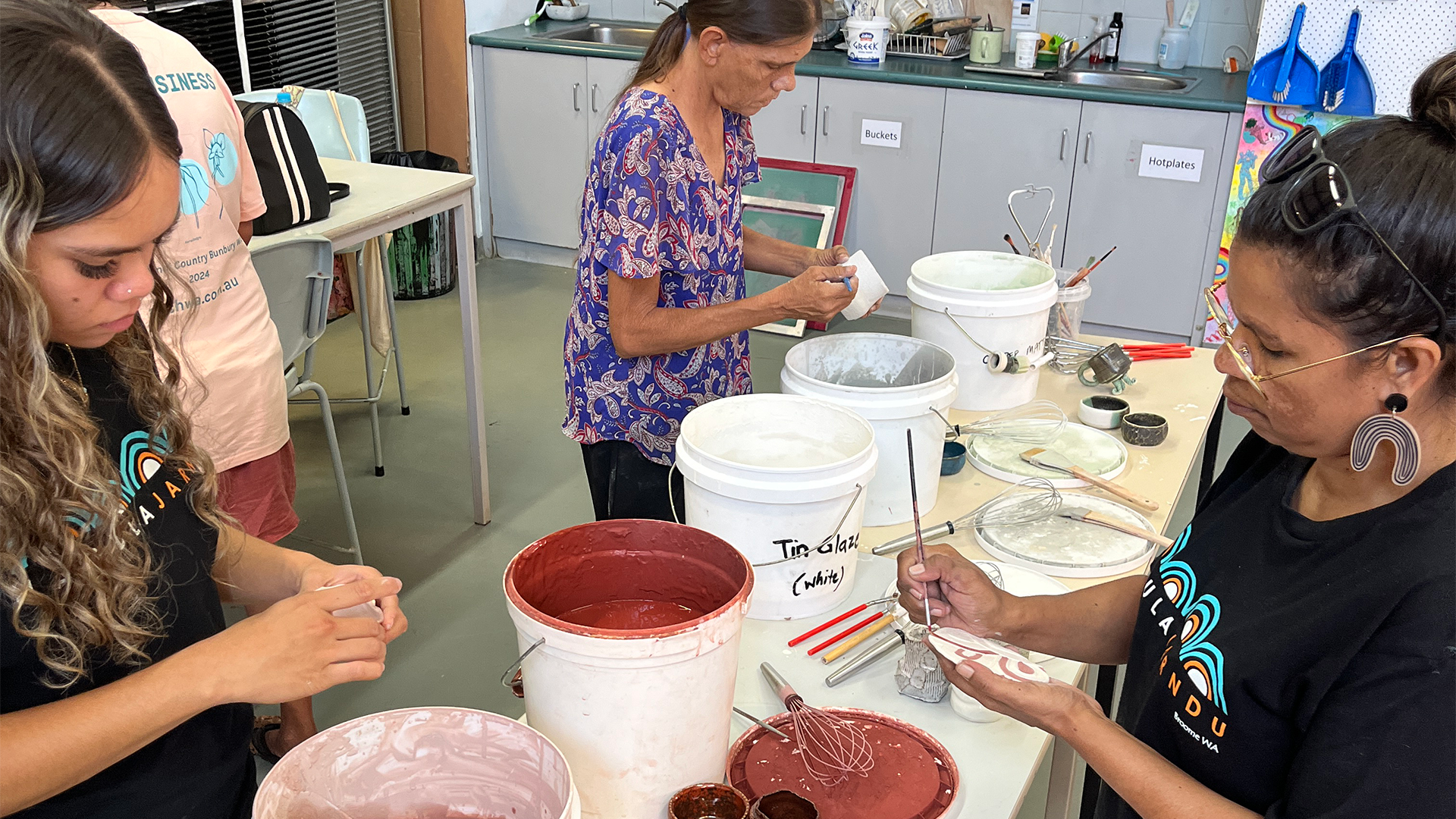 Nagula Jarndu Designs artists in the Visual arts studio at the North Regional TAFE, Broome with Lecture and artist Tanya Lee, learning how to glaze their newly made ceramics pieces. During the Our Country Moves, Rubbi (Broome) November 2024, ceramics exploration workshop. 
Photography by Tanya Lee