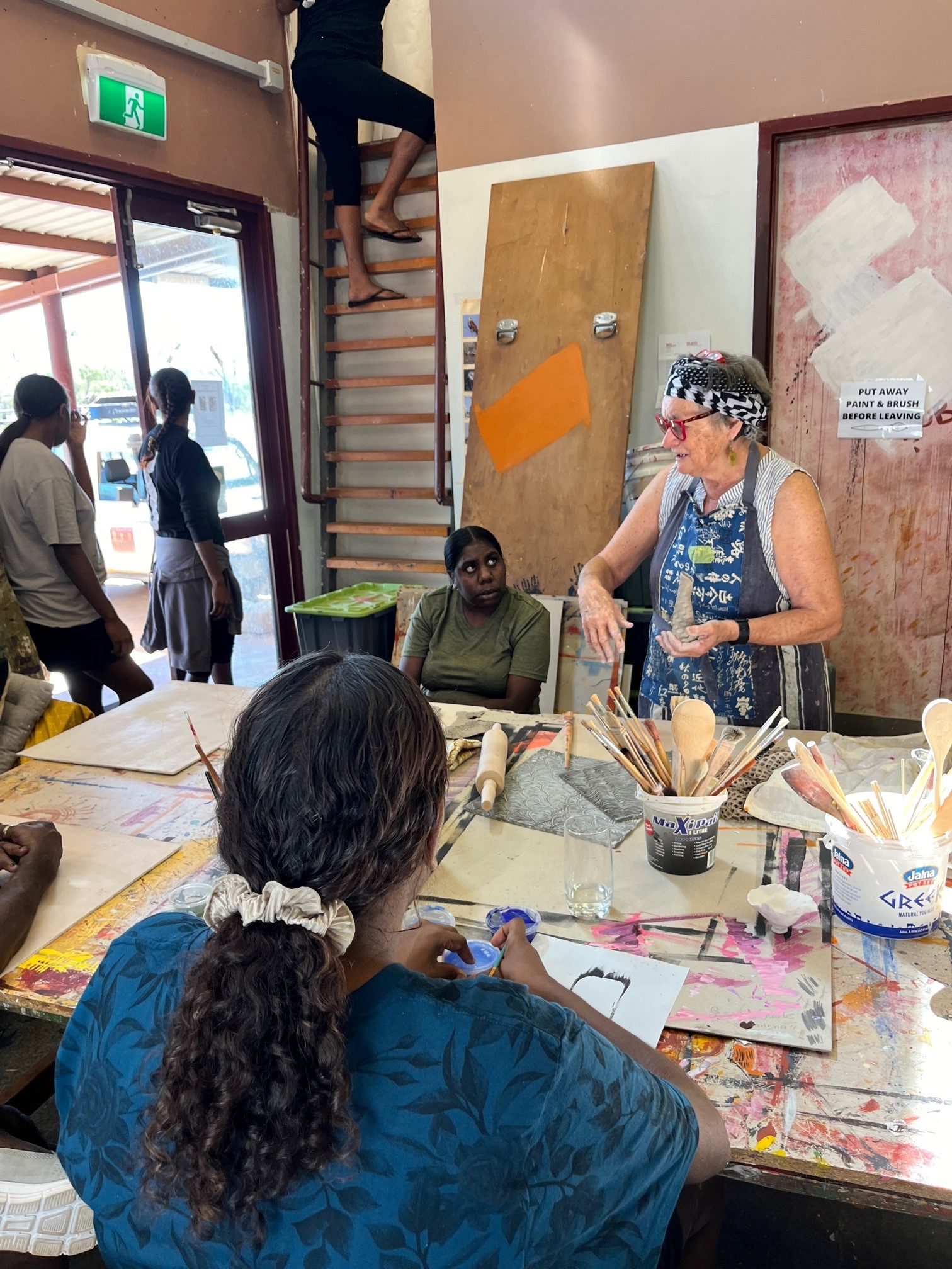 Artists from Mowanjum Arts and Cultural Centre working with facilitator Robyn Lees in the studio, creating vessels and sculptural forms, Our Country Moves Program, (Derby), 2024. Photo by AACHWA.