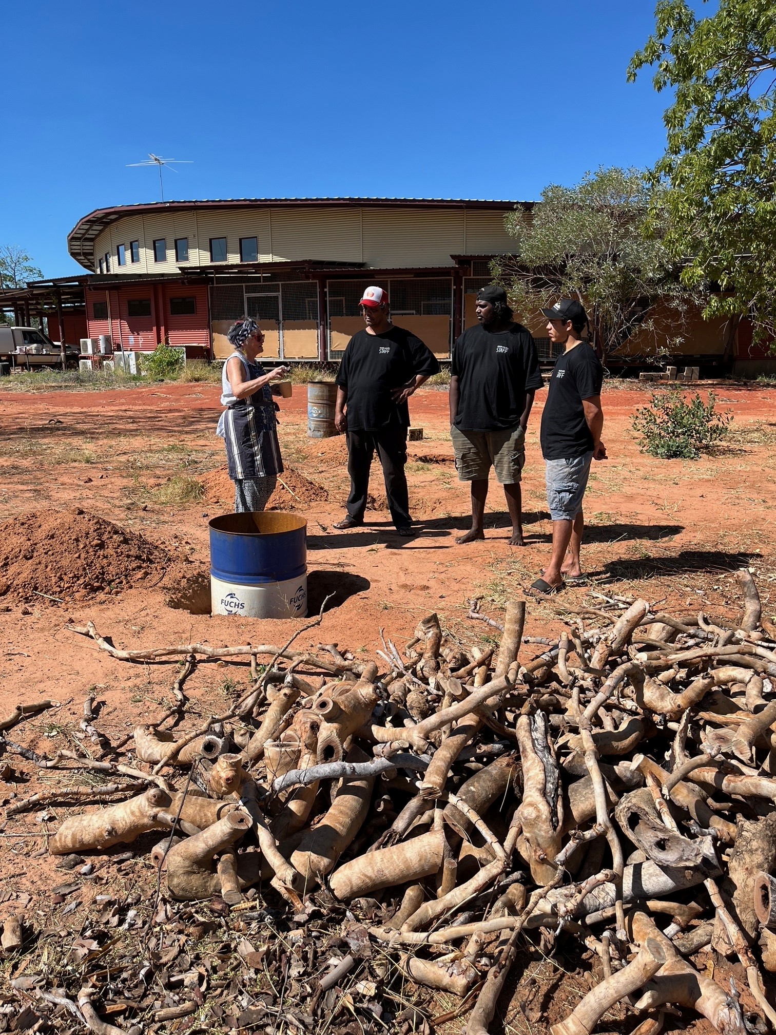 Robyn Lees and arts workers overseeing the rangers as they create fire pits for Raku firing, a traditional Japanese method of firing ceramics, at the Mowanjum Arts and Cultural Centre, Our Country Moves Program, (Derby), 2024. Photo by AACHWA. 