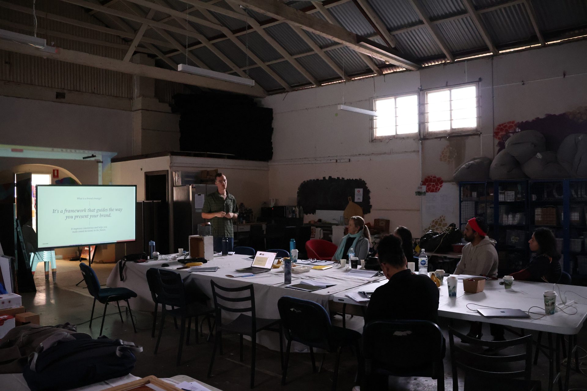 Tobie George presenting to Yamaji Art’s Marina Baker, Jennifer Green, Tamati Smith, Pelda Aktas and Roni Kerley, Our Mob Online brand discovery workshop, Yamaji (Geraldton), 2025, photo: AACHWA